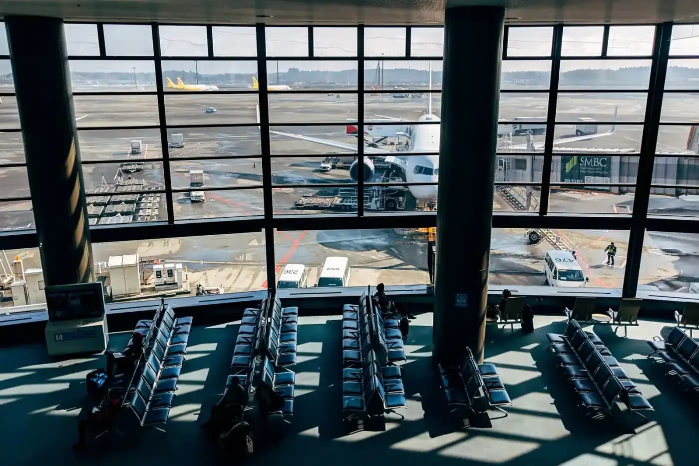 Salle d'embarquement aéroport avec vue sur les pistes et avion stationné