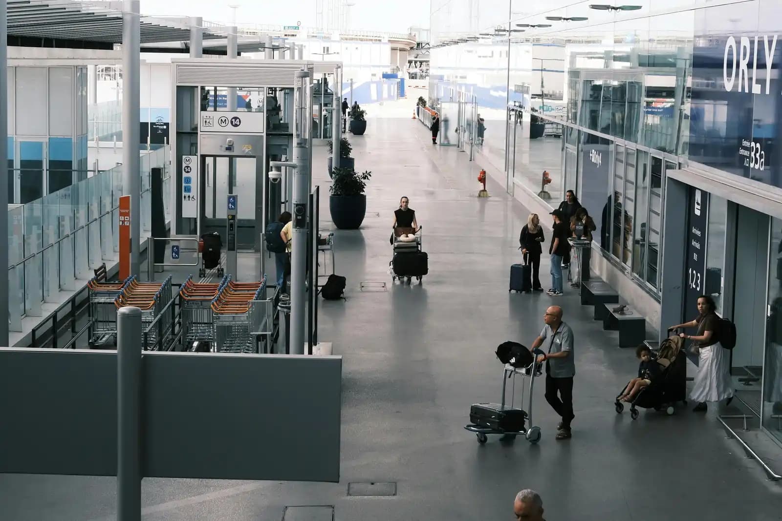 Terminal de l'aéroport Paris-Orly avec voyageurs, chariots à bagages et signalétique Orly